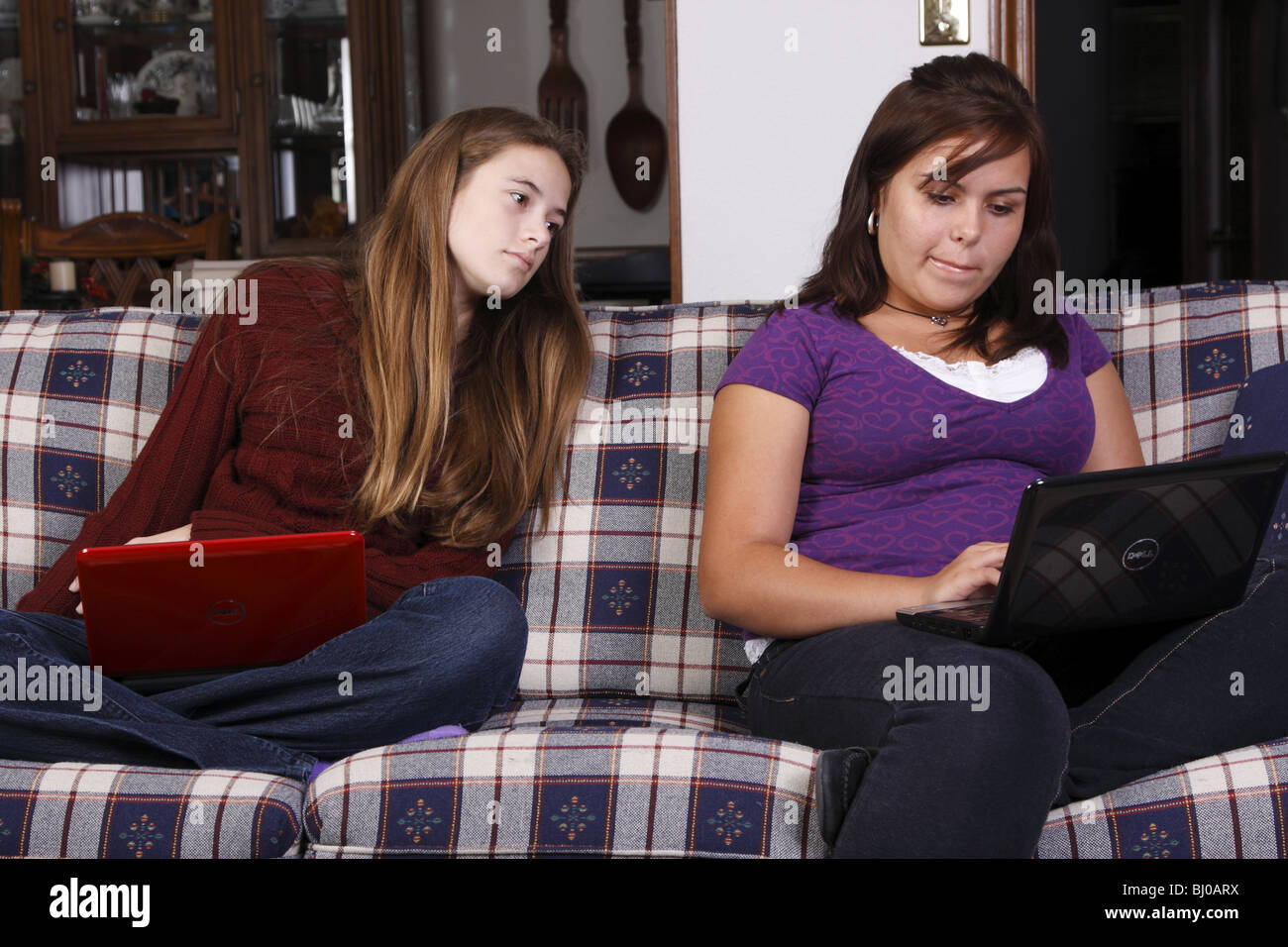 Una ragazza adolescente guardando sopra la sua spalla amici per vedere la schermata Foto Stock