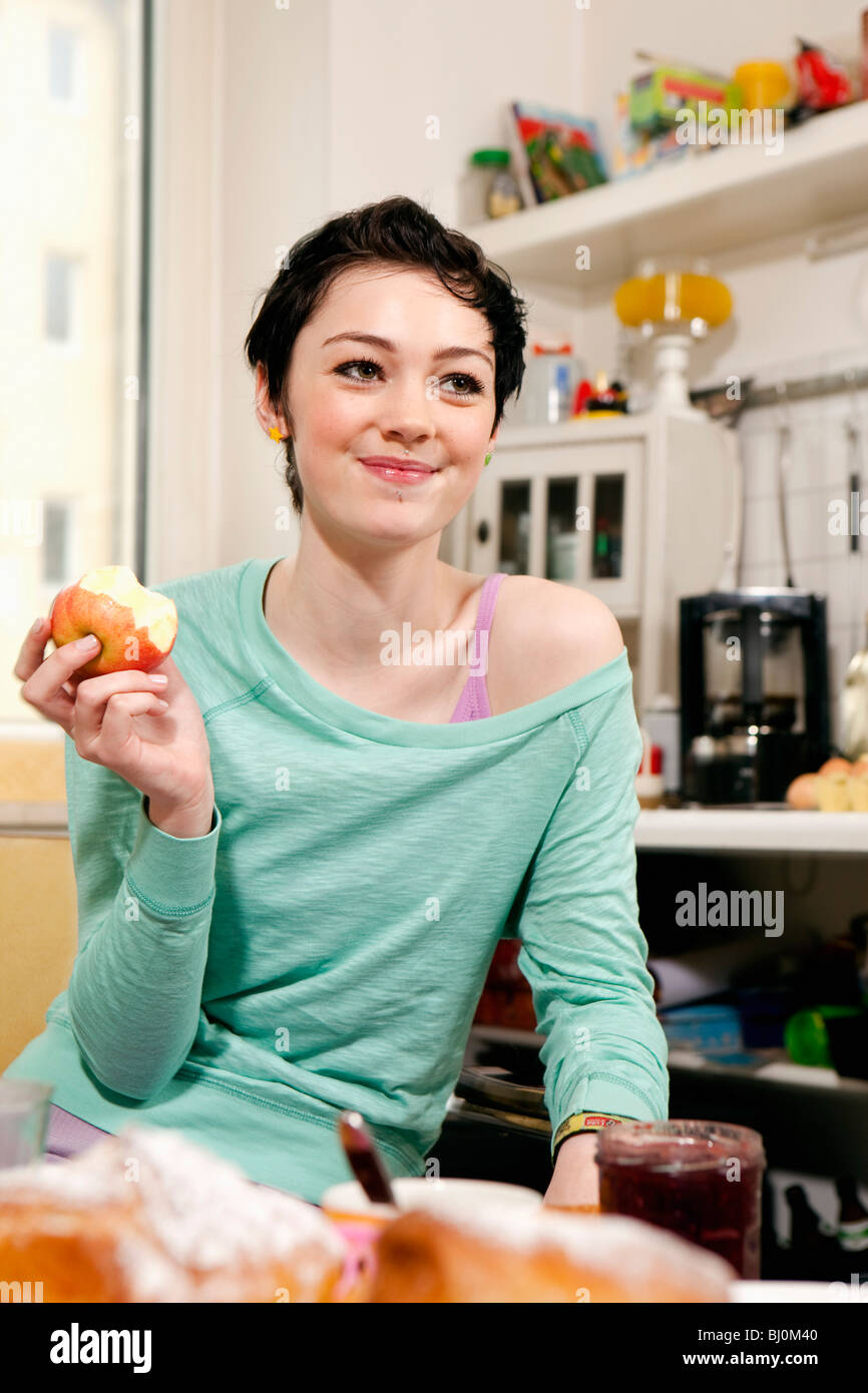 Ritratto di ragazza seduta in cucina mangiare apple Foto Stock