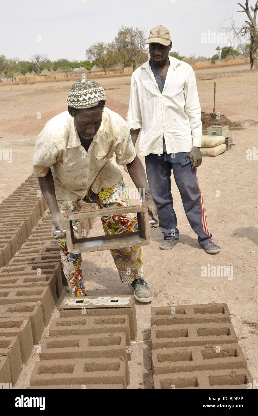 Gli uomini con il blocchetto di argilla per la costruzione di una scuola. il Gambia. Foto Stock
