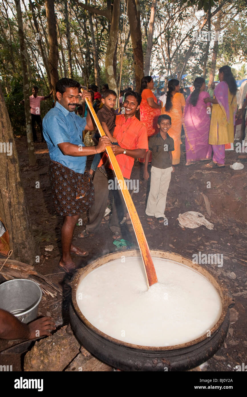 India Kerala, Kanjiramattom Kodikuthu festival musulmano, uomo pongal agitazione in enorme pentola su fuoco di legno aperto Foto Stock