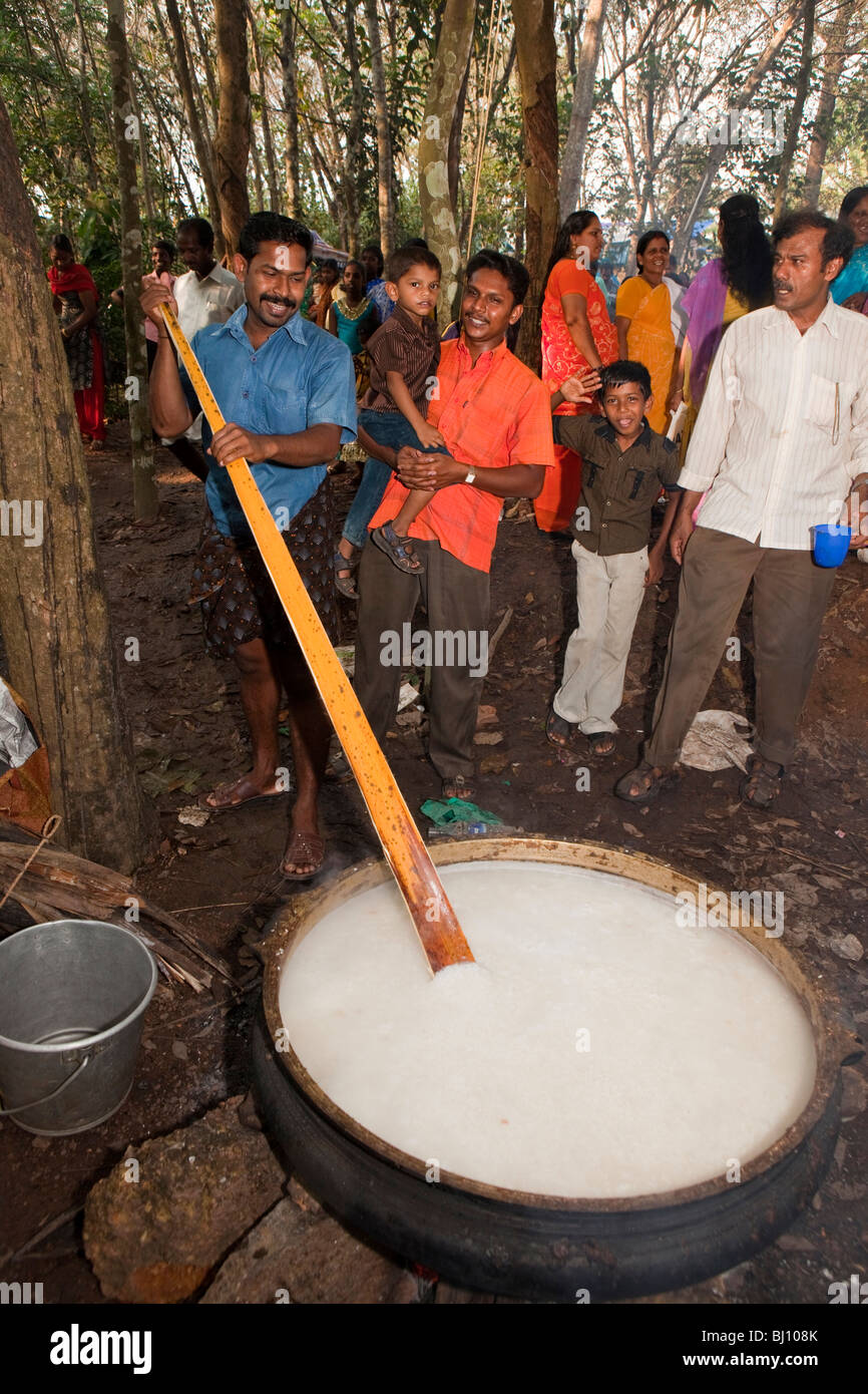 India Kerala, Kanjiramattom Kodikuthu festival, uomo pongal agitazione in enorme pentola su fuoco di legno aperto Foto Stock