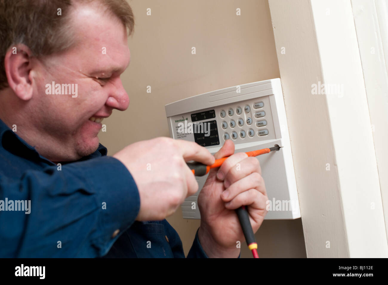 Elettricista di mettere il coperchio su un allarme antifurto in Shropshire home, Inghilterra Foto Stock