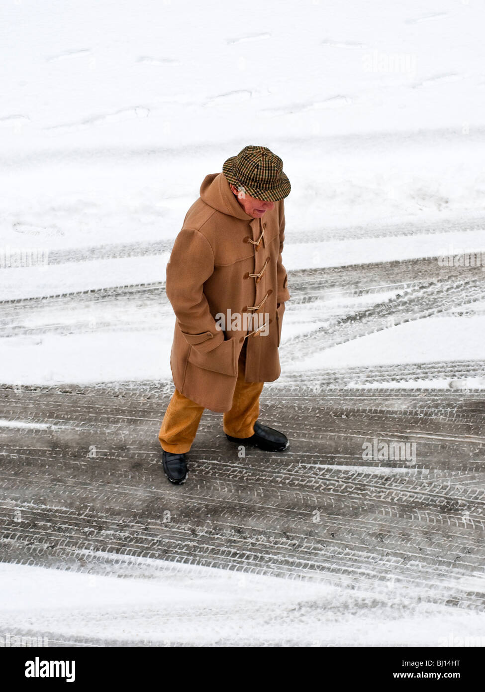 Uomo in soprabito camminando sulla coperta di neve su strada - Francia. Foto Stock