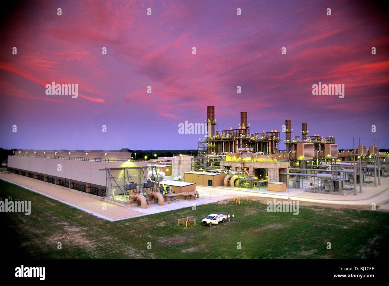 I lavoratori di utilità in piedi con un camioncino con un gas naturale fired power plant in background Foto Stock