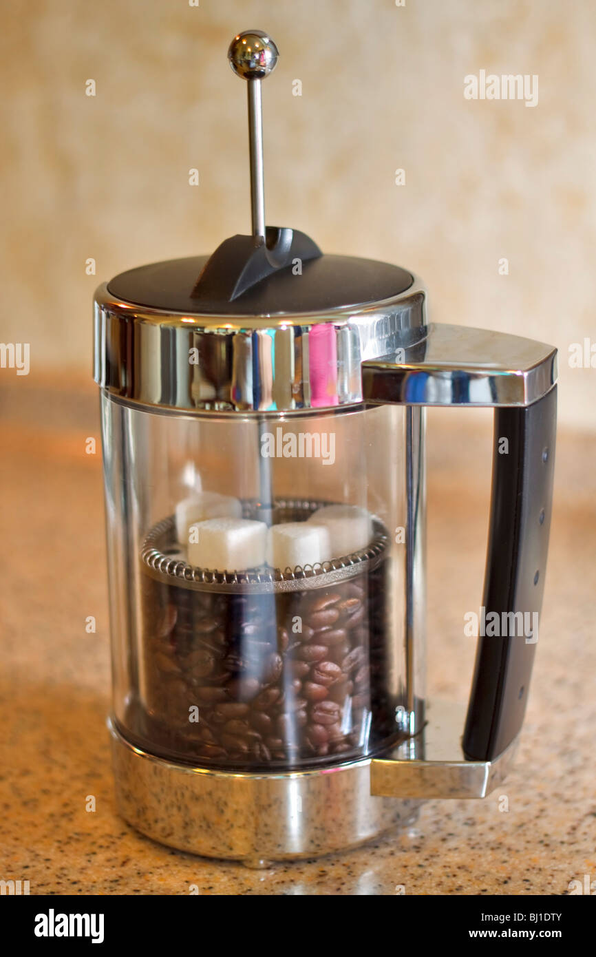 I chicchi di caffè e cubetti di zucchero in una pressa francese Foto Stock