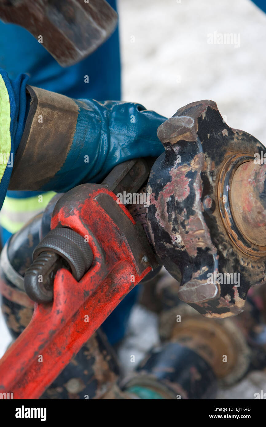 I lavoratori con una chiave a tubo il serraggio a unirsi in una operazione di esplorazione petrolifera Foto Stock