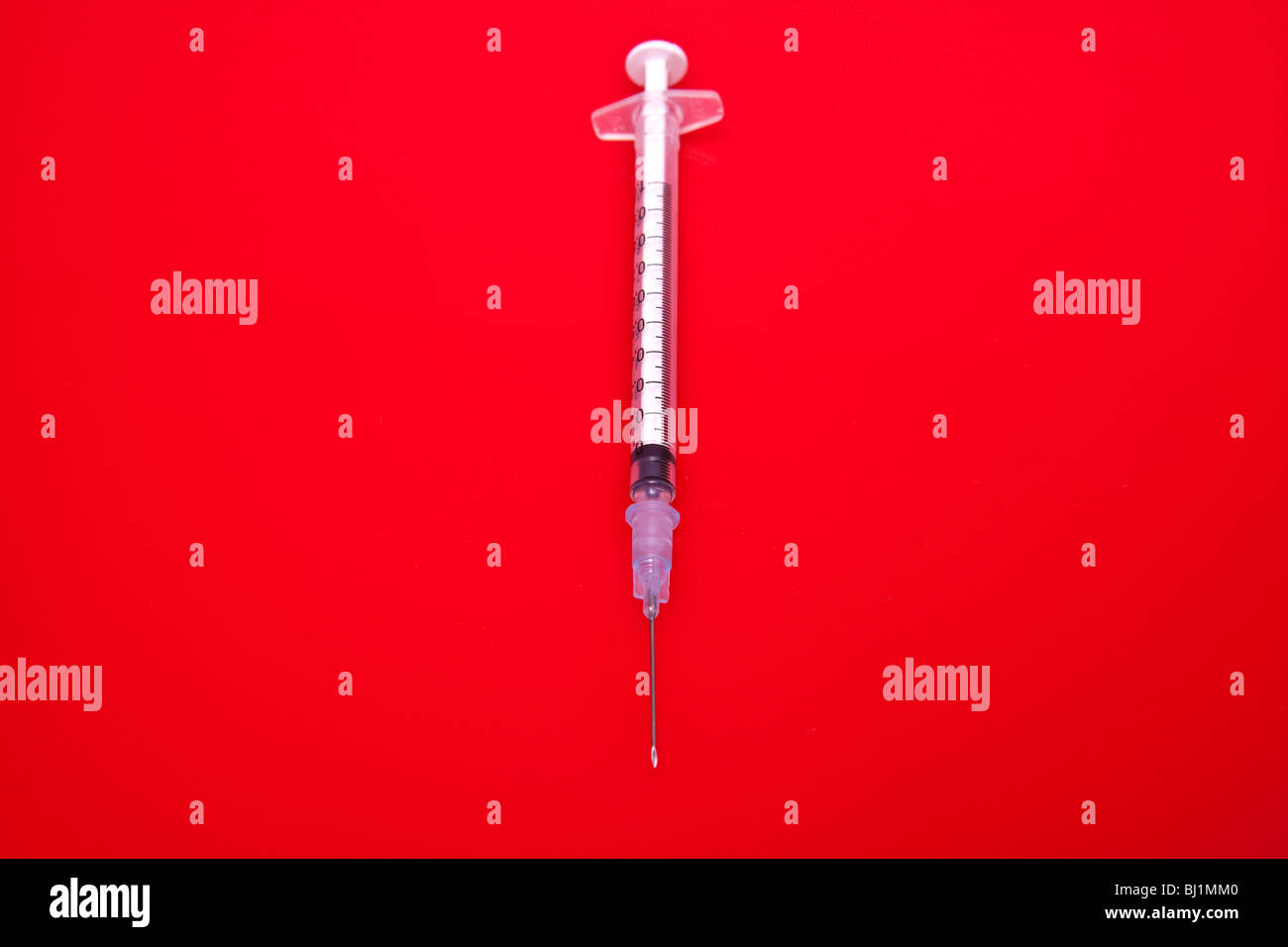Ago e siringa su una rossa di sfondo per studio. Foto Stock
