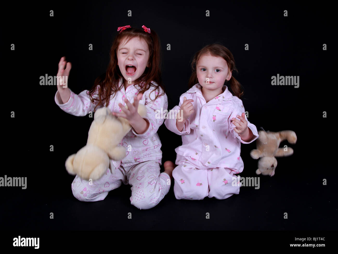 Sorelle in rosa pigiama con i loro orsetti di peluche. Foto Stock