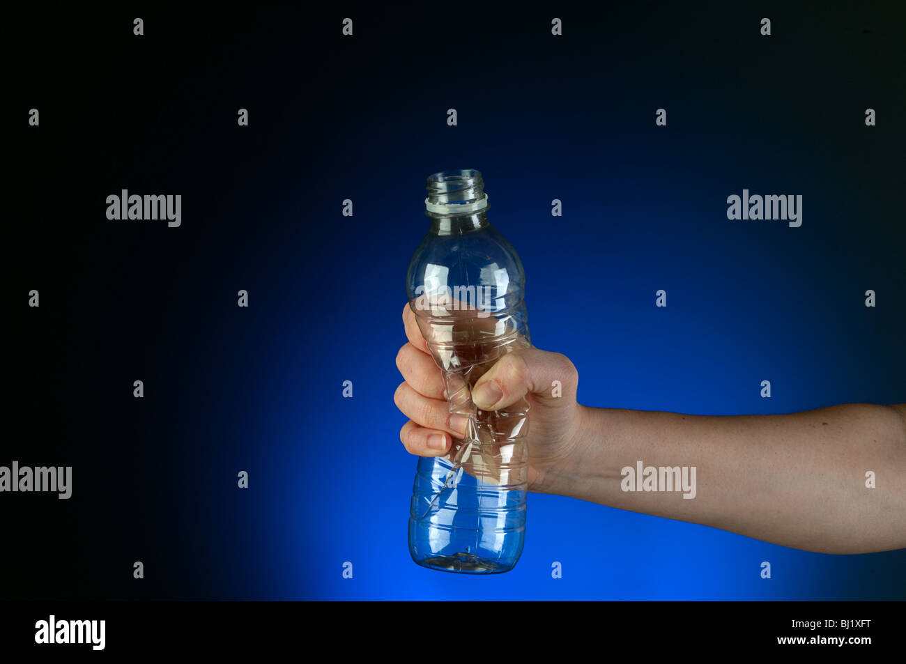 L'immagine orizzontale di una mano la frantumazione di materiale plastico riciclabile in un bagliore blu sullo sfondo Foto Stock
