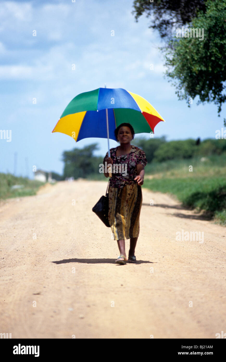 Una signora dello Zimbabwe mantiene il sole fuori la sua testa con un ombrello Foto Stock