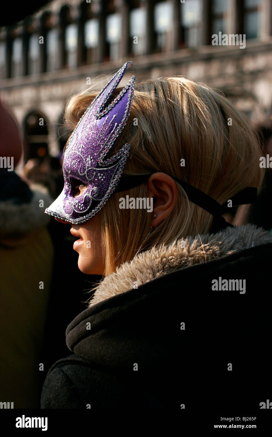 Ragazza bionda durante il Carnevale di Venezia con una maschera viola Foto Stock