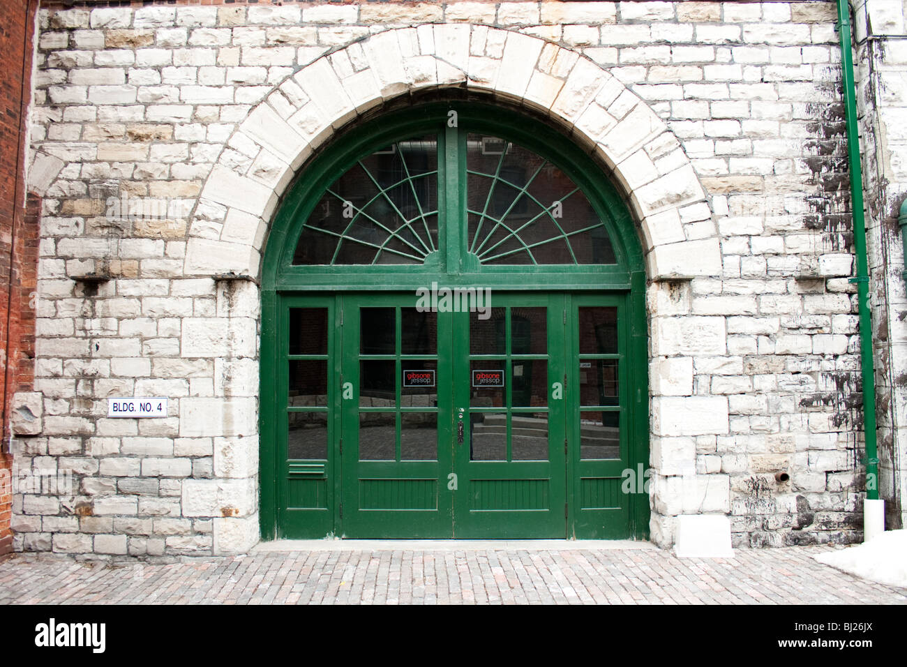 Il verde della porta d'ingresso di un vecchio edificio in mattoni bianchi Foto Stock
