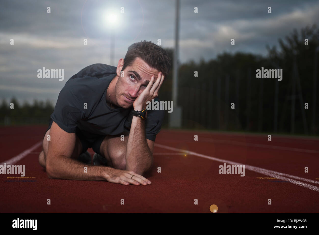 Atleta maschio accovacciato in disperazione Foto Stock