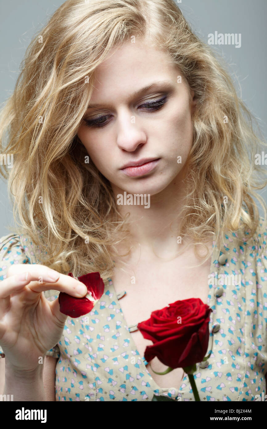 Donna tirando i petali off una rosa Foto Stock