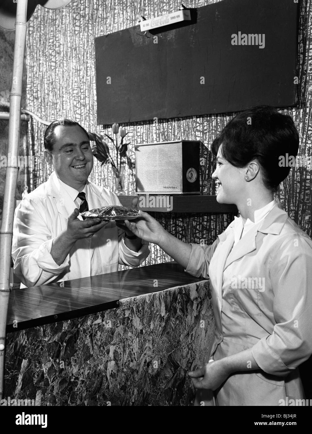 Servire un pasto a un cliente in un bar, Mexborough, South Yorkshire, 1964. Artista: Michael Walters Foto Stock