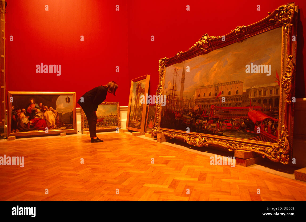Un curatore ispeziona tele arte appoggiata contro le pareti della gallery in la Royal Academy (RA) per la sua "la Gloria di Venezia' show. Foto Stock