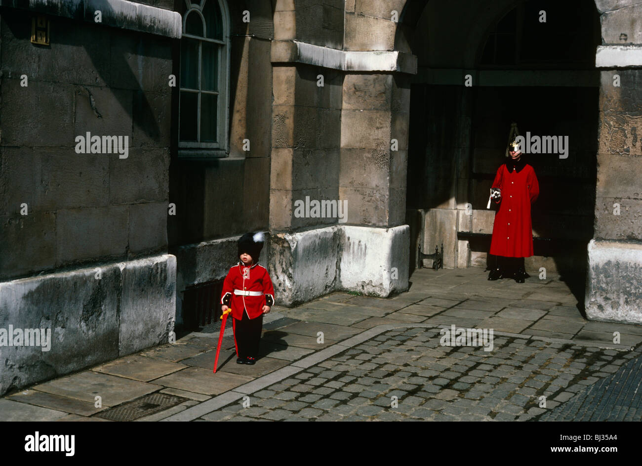 Un giovane ragazzo di circa 5 anni a Horse Guards in cui un soldato di cavalleria della famiglia indossa simile rosso uniforme. Foto Stock