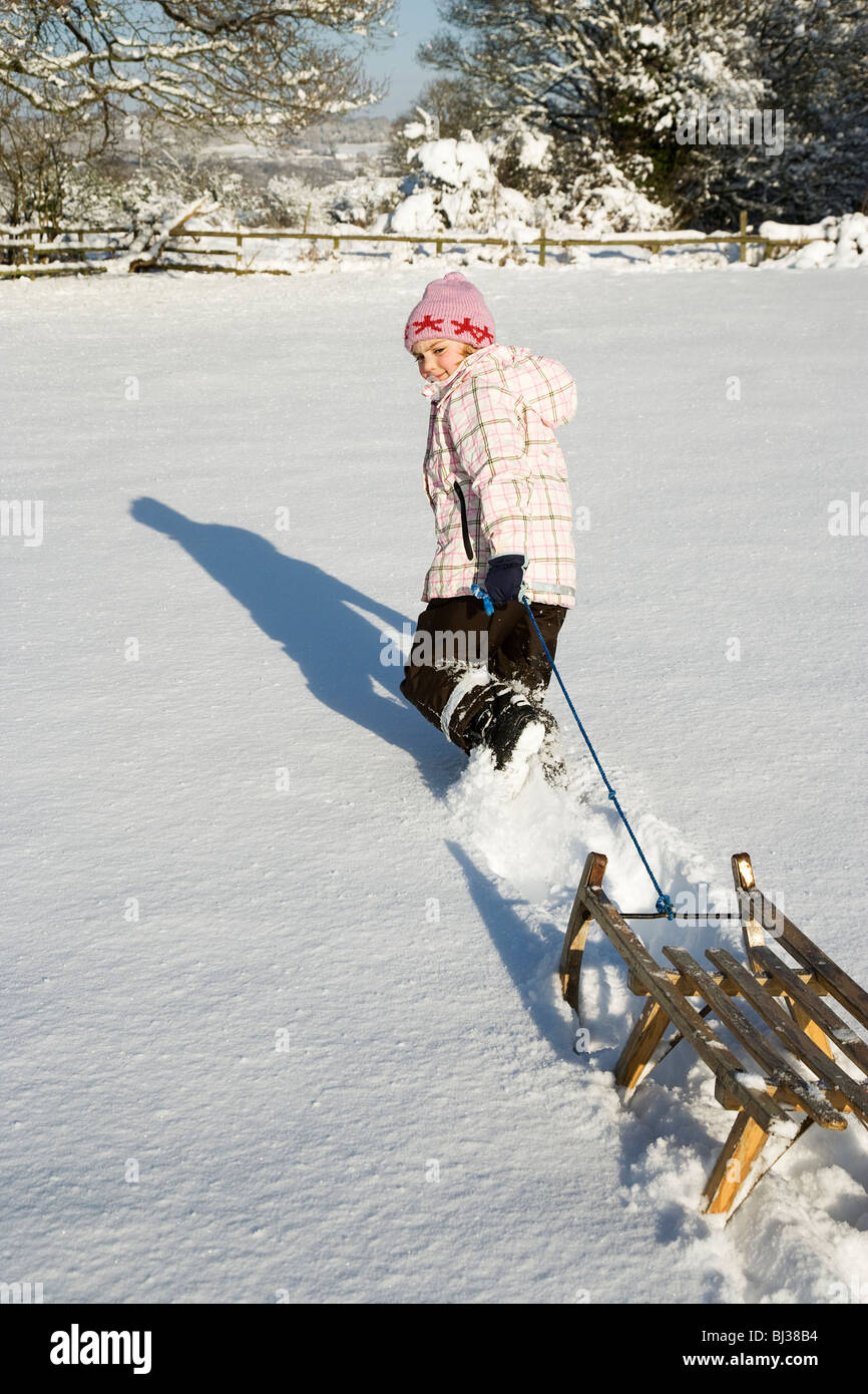 Ragazza giovane tirando la slitta nella neve Foto Stock