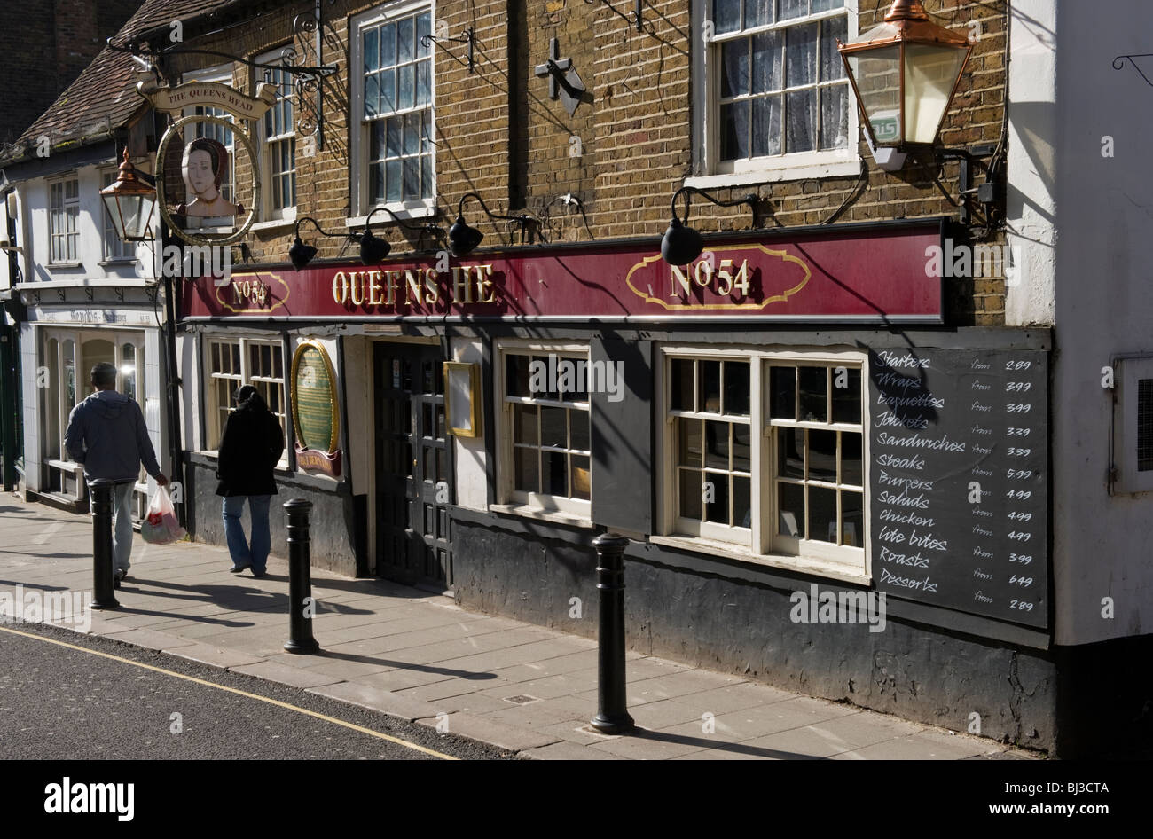 Due persone a camminare lungo la Queens Head una banchina pub di Uxbridge Town Center West London. Foto Stock