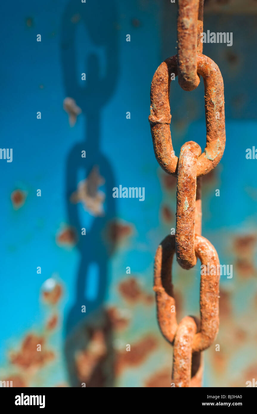 Acciaio arrugginito maglie di catena a sunshine contro rusty sfondo blu Foto Stock