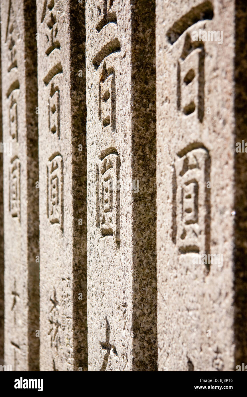 Vista ravvicinata lungo quattro tavolette in pietra, con i nomi dei benefattori incisi su di esse presso il santuario di Kiyoshikojin Seichoji a Takarazuka, Giappone. Foto Stock