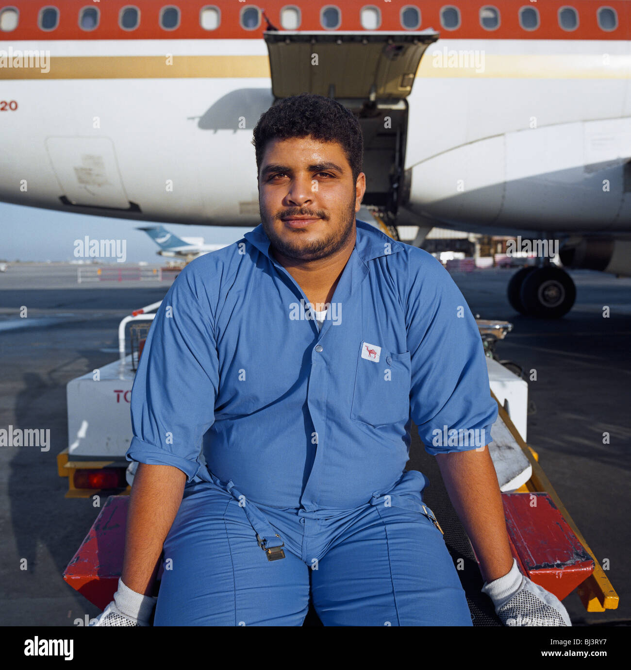 Un bagaglio Bahrani-handler impiegato da SABTCO pause durante il suo spostamento sul Bahrain International Airport. Foto Stock