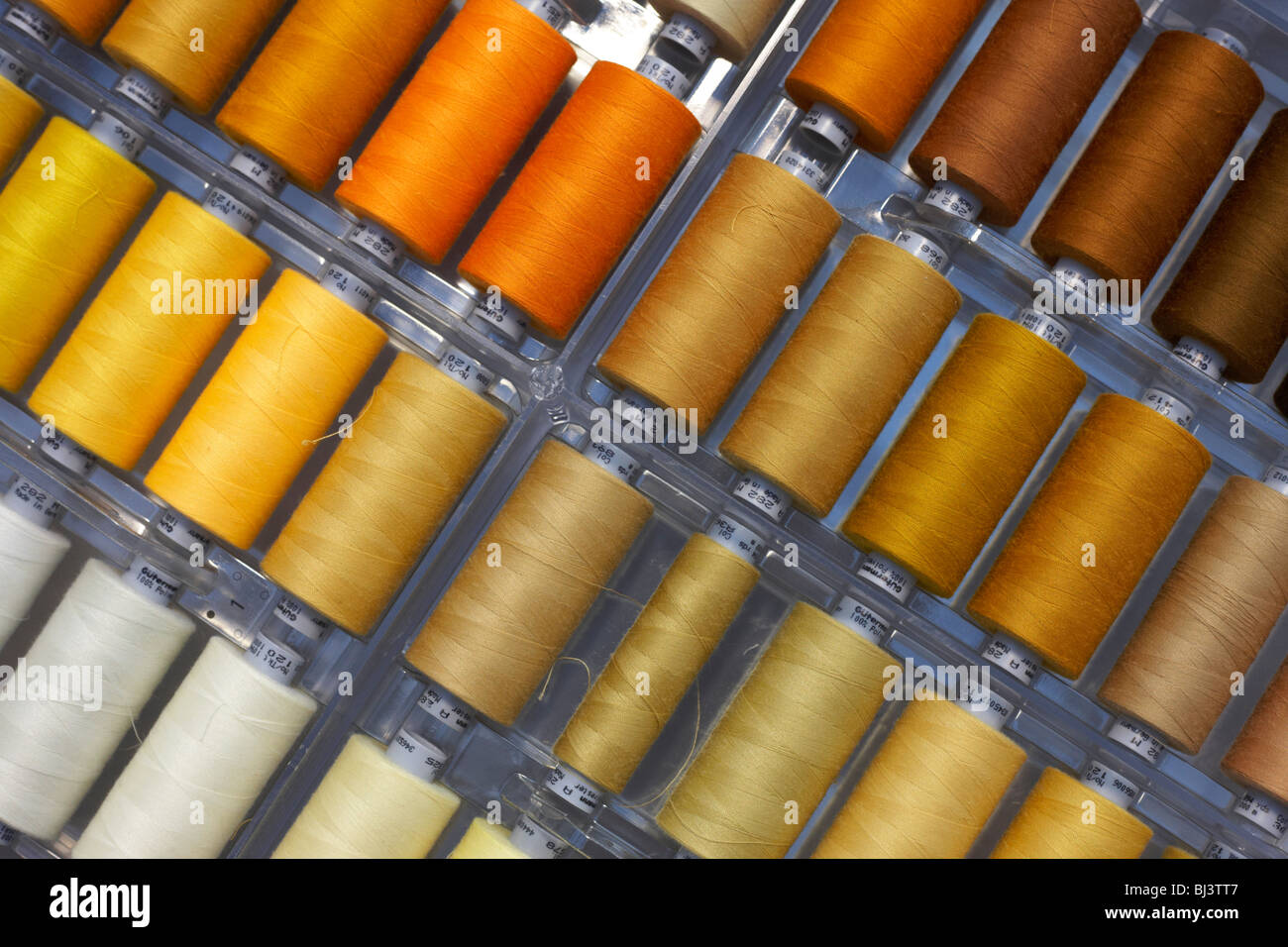 Sfumature di giallo e marrone i fili di cotone sono visti in un cassetto aperto utilizzato da couturier Margaret Howell. Foto Stock