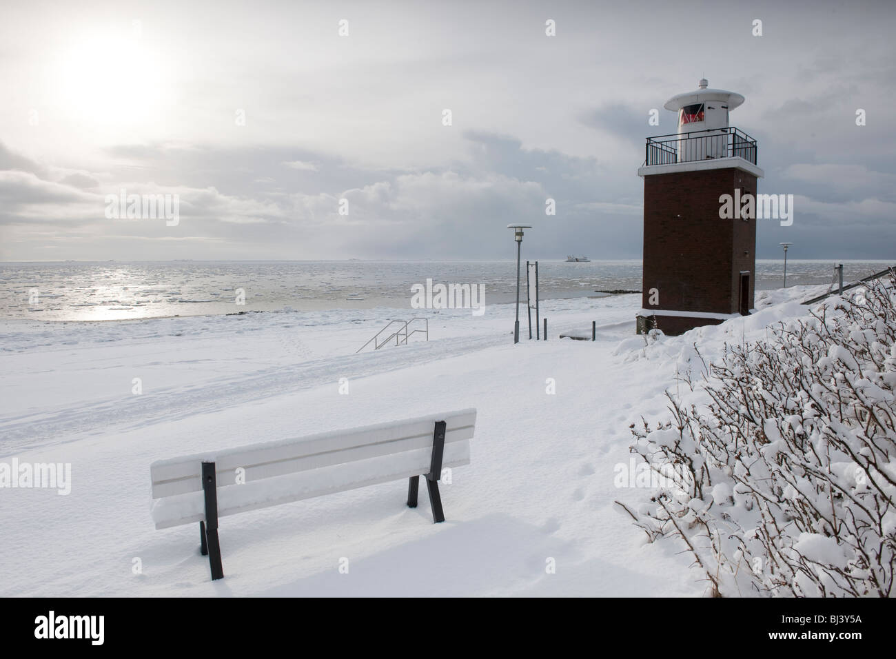 Il Olhoern faro sulla neve spiaggia sud di Wyk, isola del Mare del Nord di Foehr, all'orizzonte la terraferma con il traghetto, Nationalpark Foto Stock