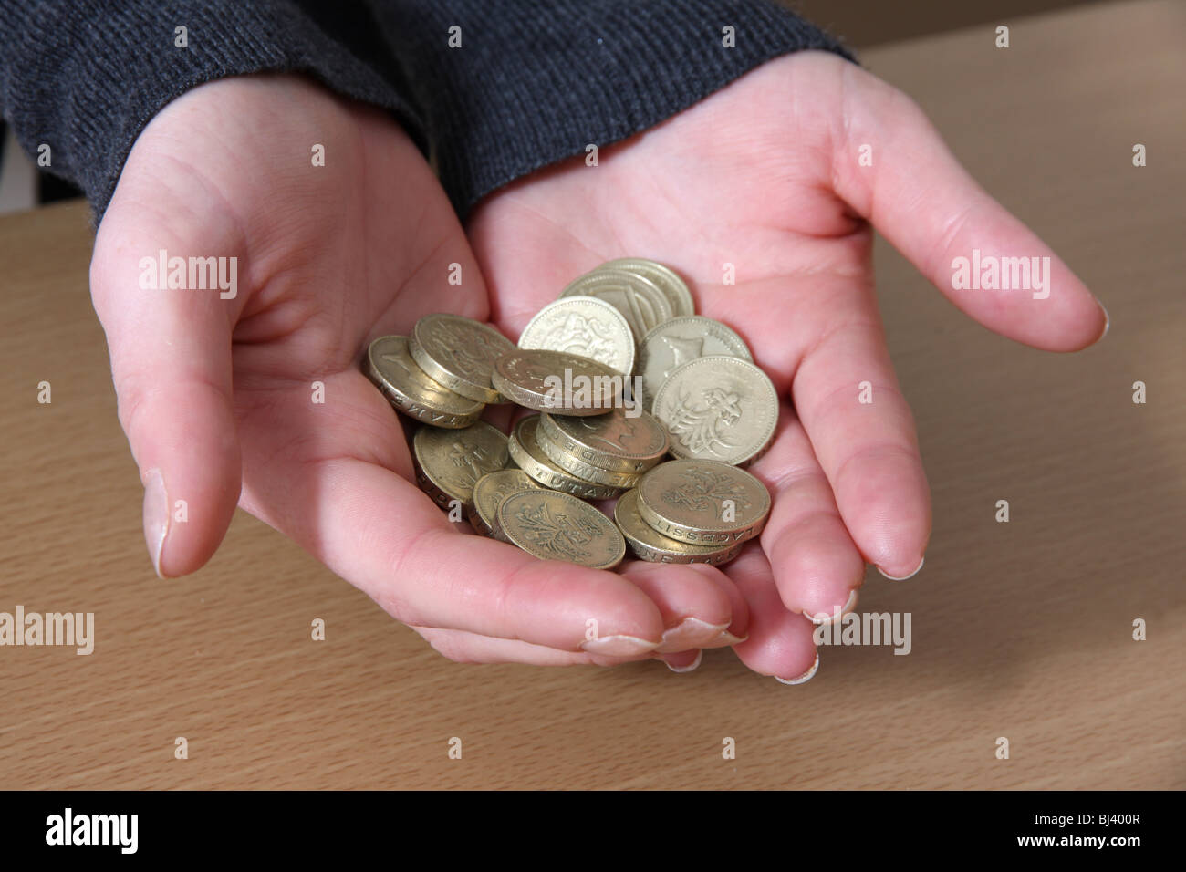Mani femminili tenendo qualche sterlina inglese monete. Foto Stock