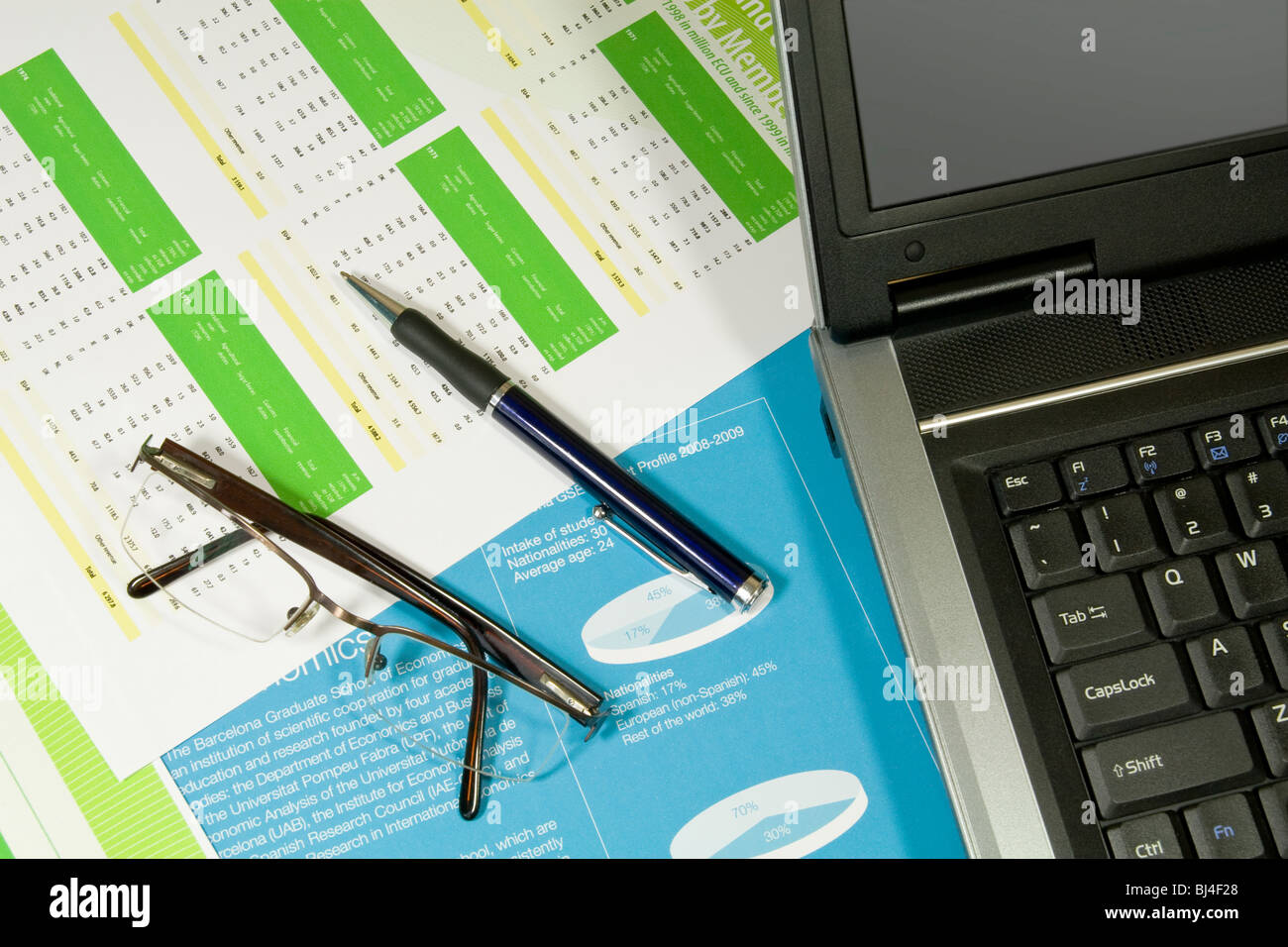 Laptop, penna e occhiali in relazione finanziaria Foto Stock