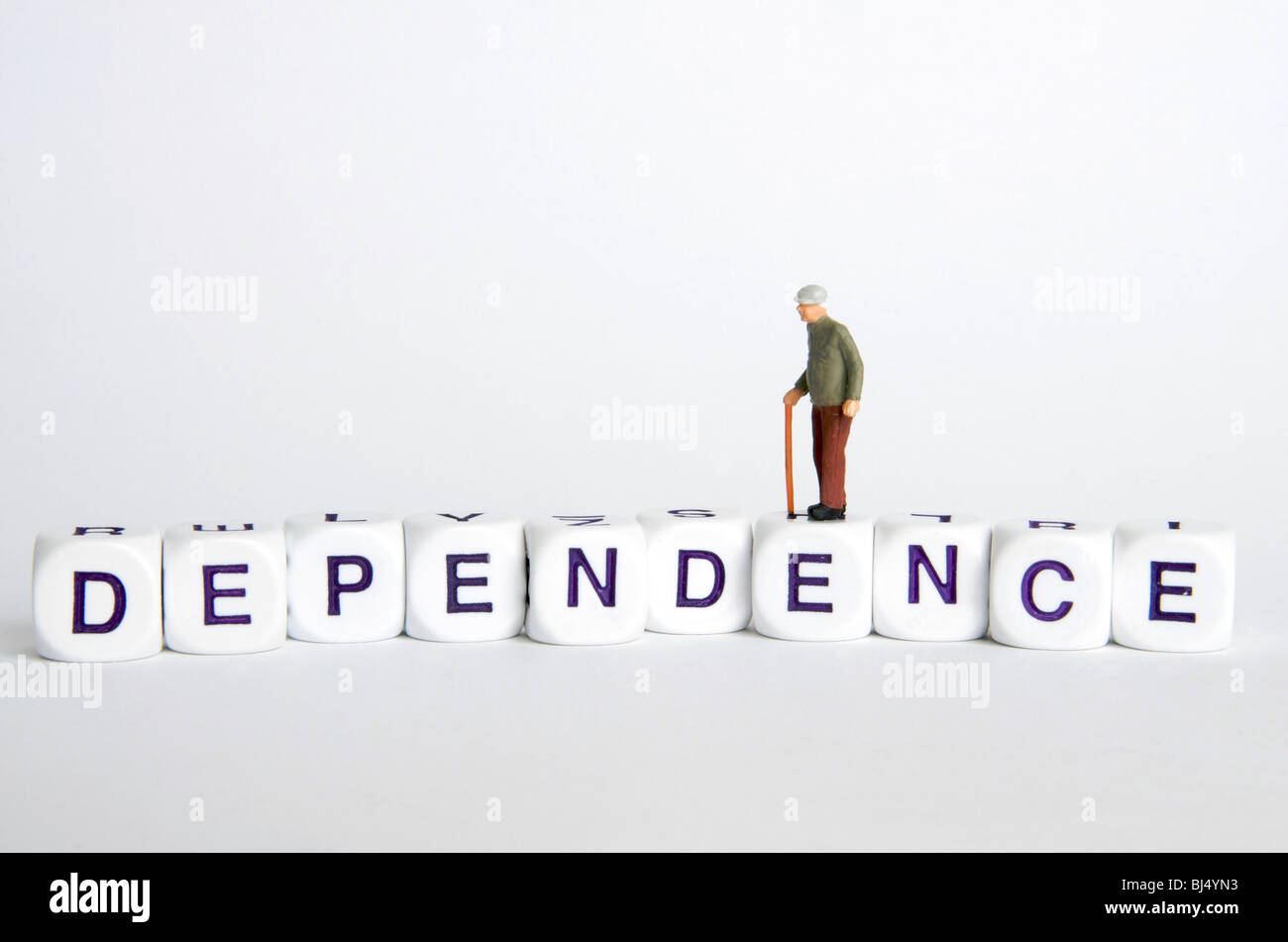 Dipendenza anziani / concetto di indipendenza - vecchio uomo figura permanente sulla parola "dipendenza". Foto Stock