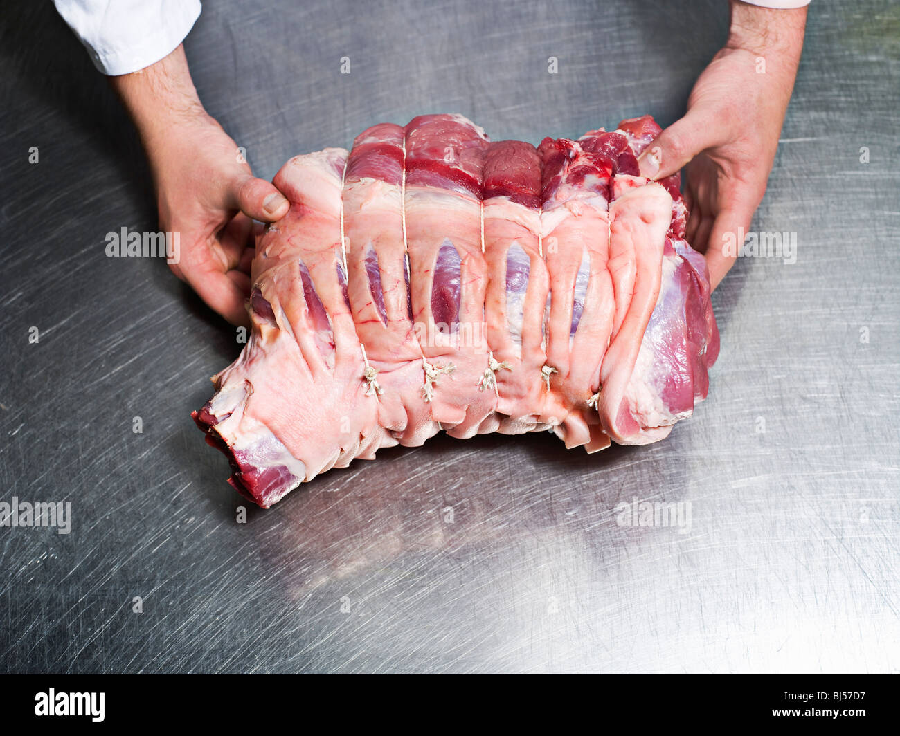 Un macellaio tenendo in mano un pezzo di carne Foto Stock