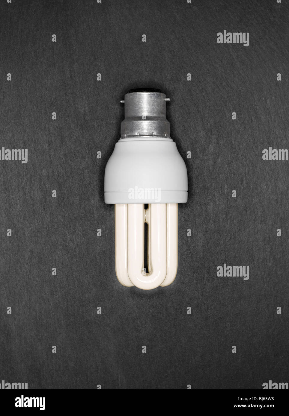 Warm Energy Saver lampadina luce su un grigio Sfondo ardesia Foto Stock