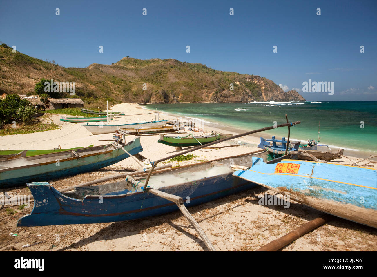 Indonesia, Lombok, South Coast, Mawun, spiaggia, i visitatori a prendere il sole tra colorfully dipinto barche da pesca Foto Stock