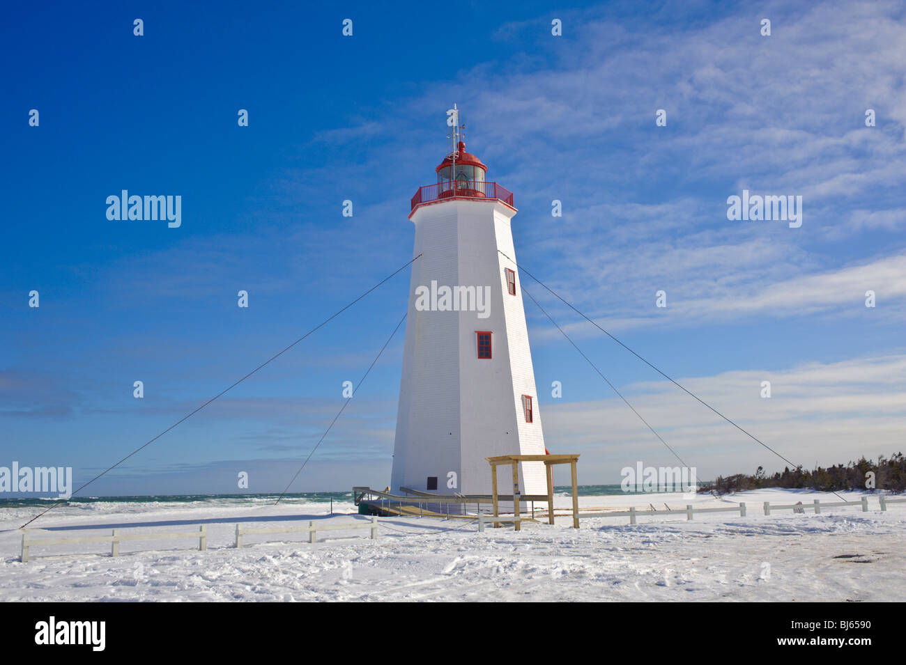 Miscou Island Lighthouse circondato dalla neve e molto un cielo blu. Inverno in Canada Foto Stock