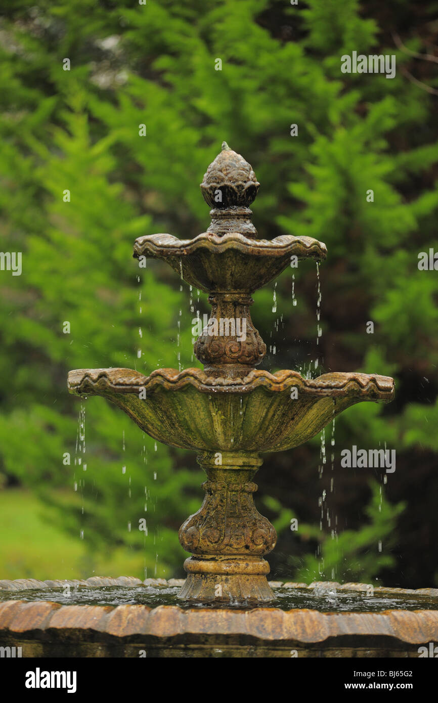 Fontana a più livelli con acqua che gocciolava giù da una ciotola per la prossima contro lo sfondo di alberi Foto Stock