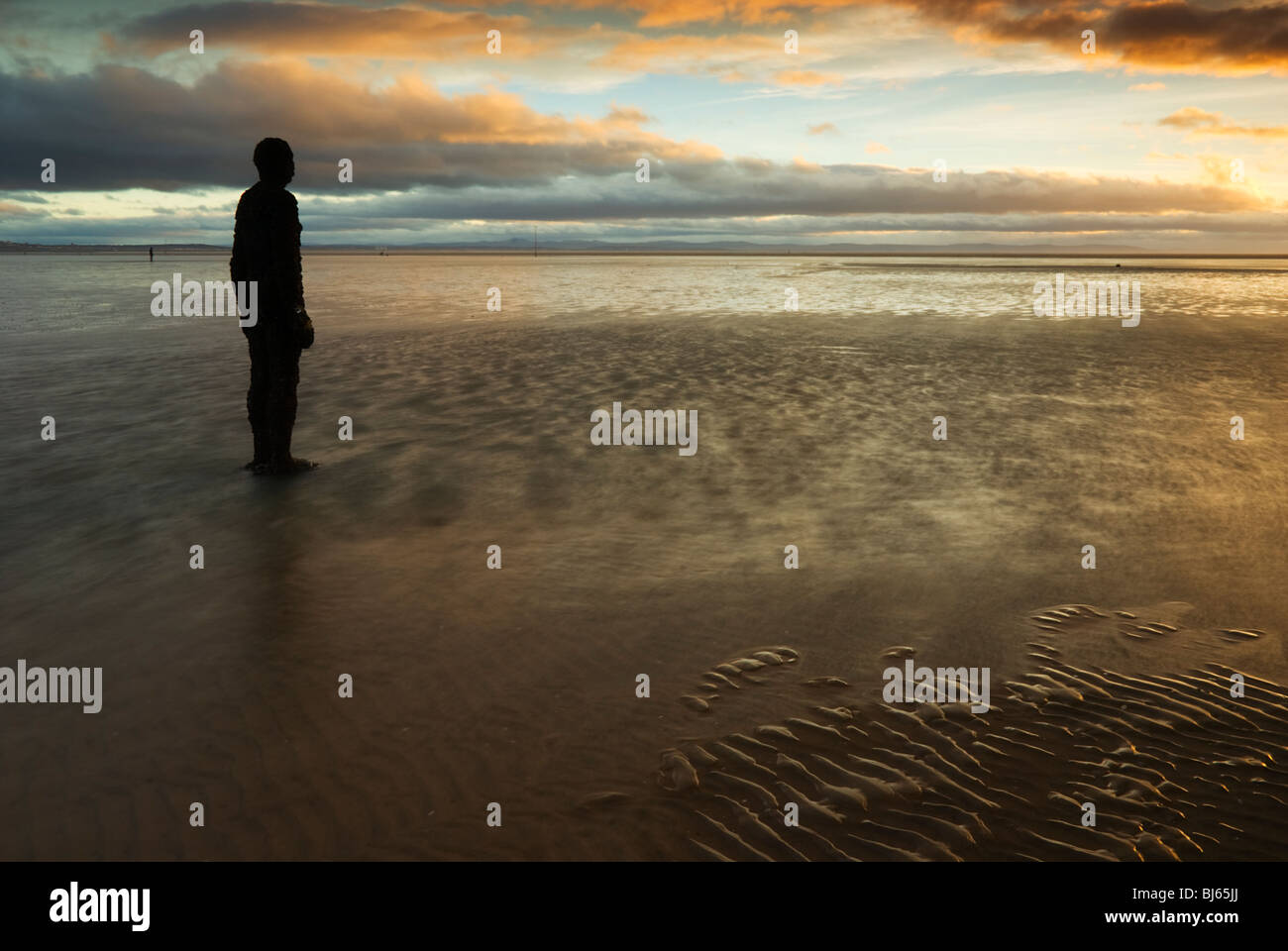 Colouful tramonto a Crosby beach, con uno di Anthony Gormly statue Foto Stock