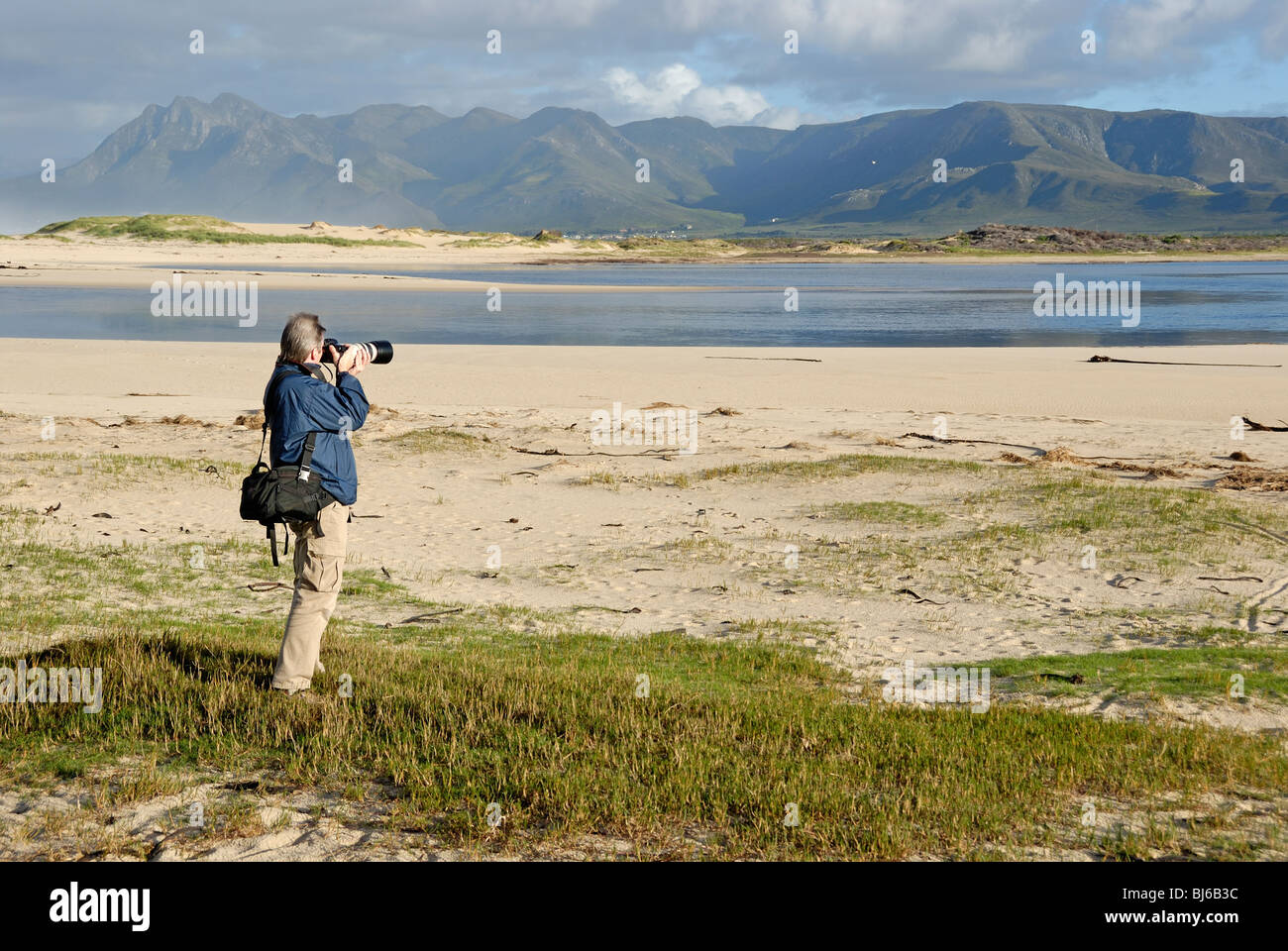 L'uomo prendendo fotografia di un paesaggio con teleobiettivo al mattino, Flamingo estuario del lago vicino a Hermanus, Sud Africa Foto Stock