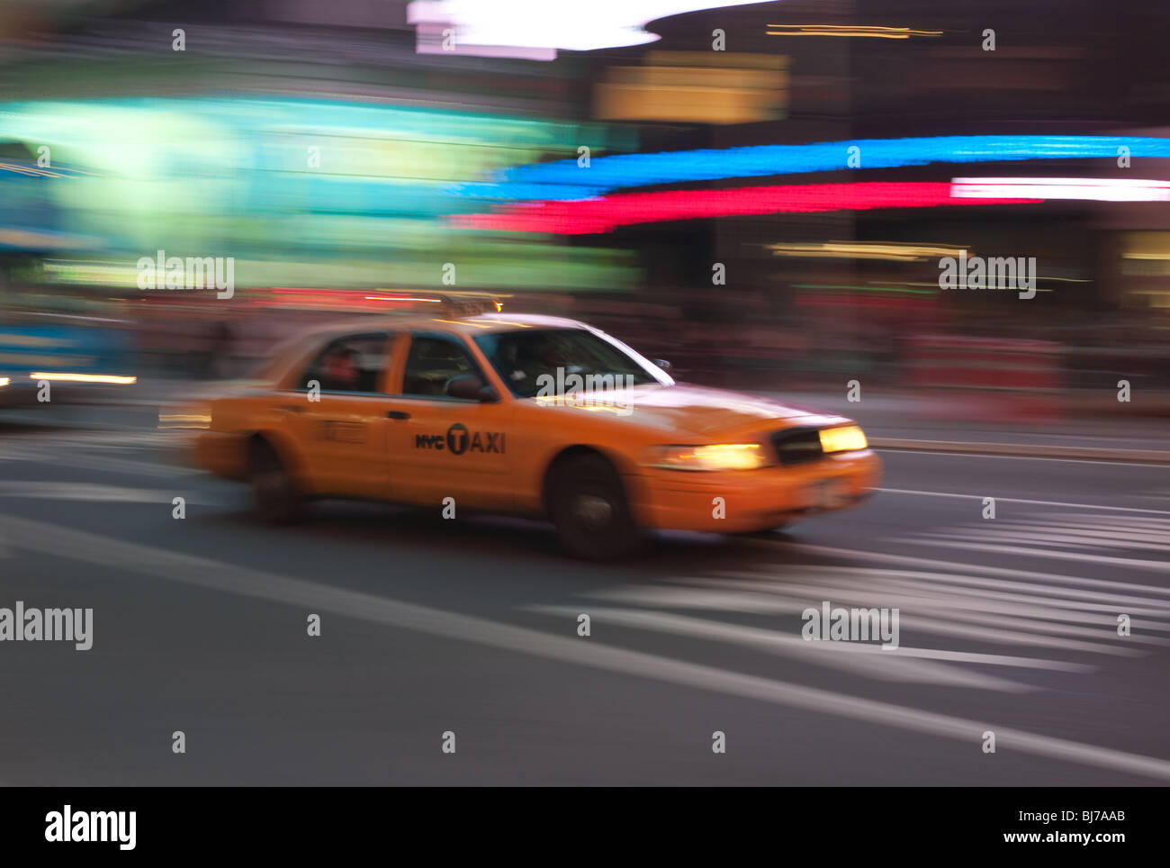 Un giallo taxi è una sfocatura come si precipita attraverso le luci di Times Square di notte a New York City. Foto Stock