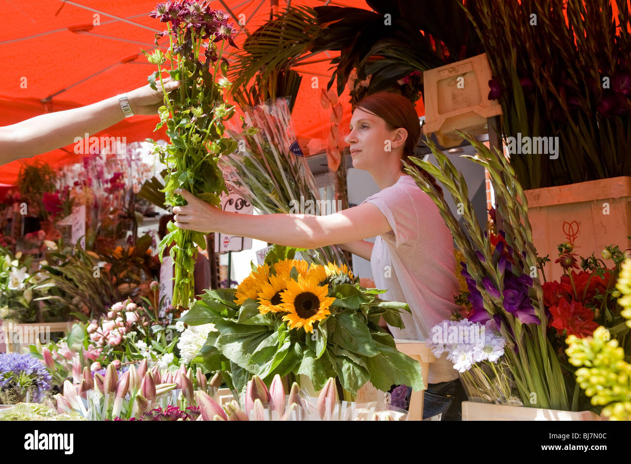 Donna che vendono fiori a Columbia road flower market, Londra, Regno Unito, Europa Foto Stock