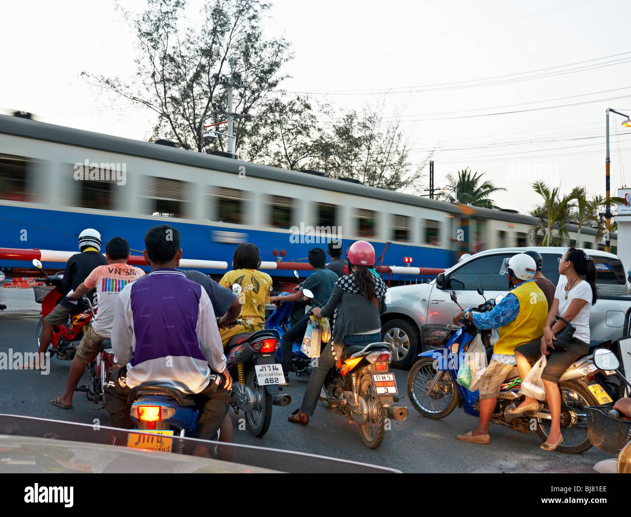 Treno livello incrocio con persone in attesa di un treno in movimento passa. Hua Hin Tailandia SUDEST ASIATICO Foto Stock