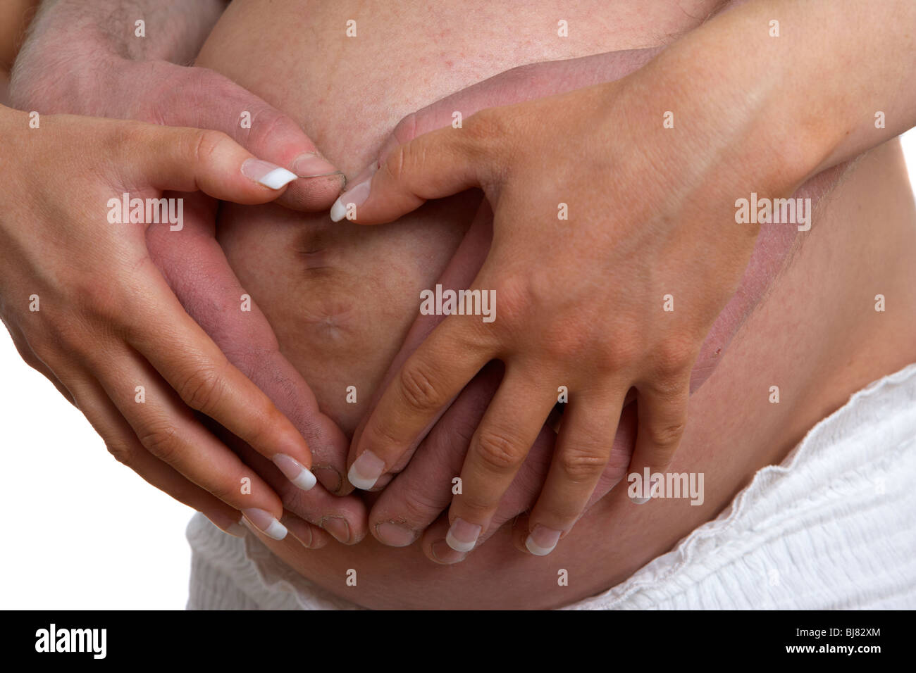 8 mese di gravidanza 30 anno vecchia donna con 37 anni partner di sesso maschile tenendo le mani sul baby bump Foto Stock
