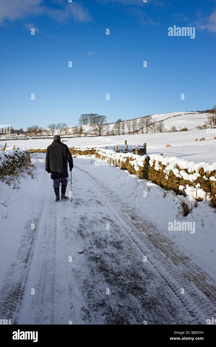 Uomo che cammina sulla strada innevata UK Winter 2010 Foto Stock