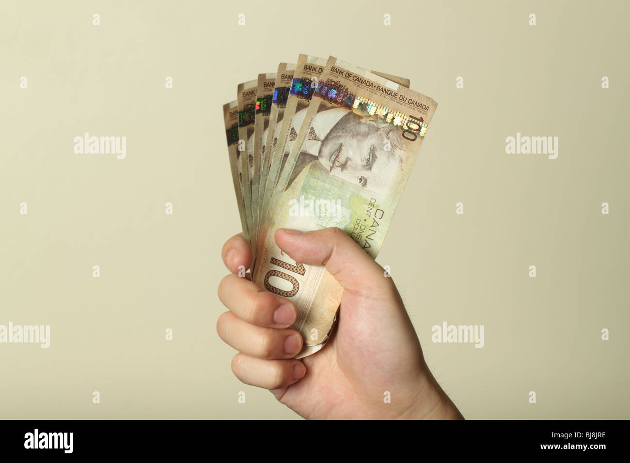 Una mano che tiene una pila di Canadian banconote da cento dollari. Foto Stock