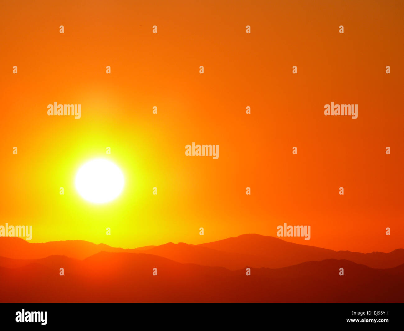 Sole arancione si accende di burst luminoso nel cielo occidentale. Foto Stock