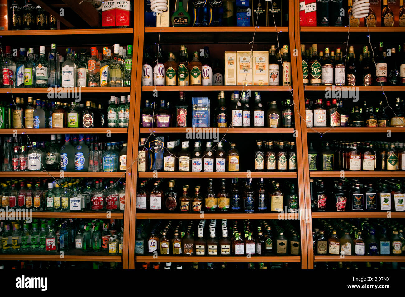 India Kerala, Mahe (Pondicherry) il territorio dell' Unione, a buon mercato delle vendite di alcolici, ben fornito Wine Shop scaffali la vendita di bevande alcoliche Foto Stock