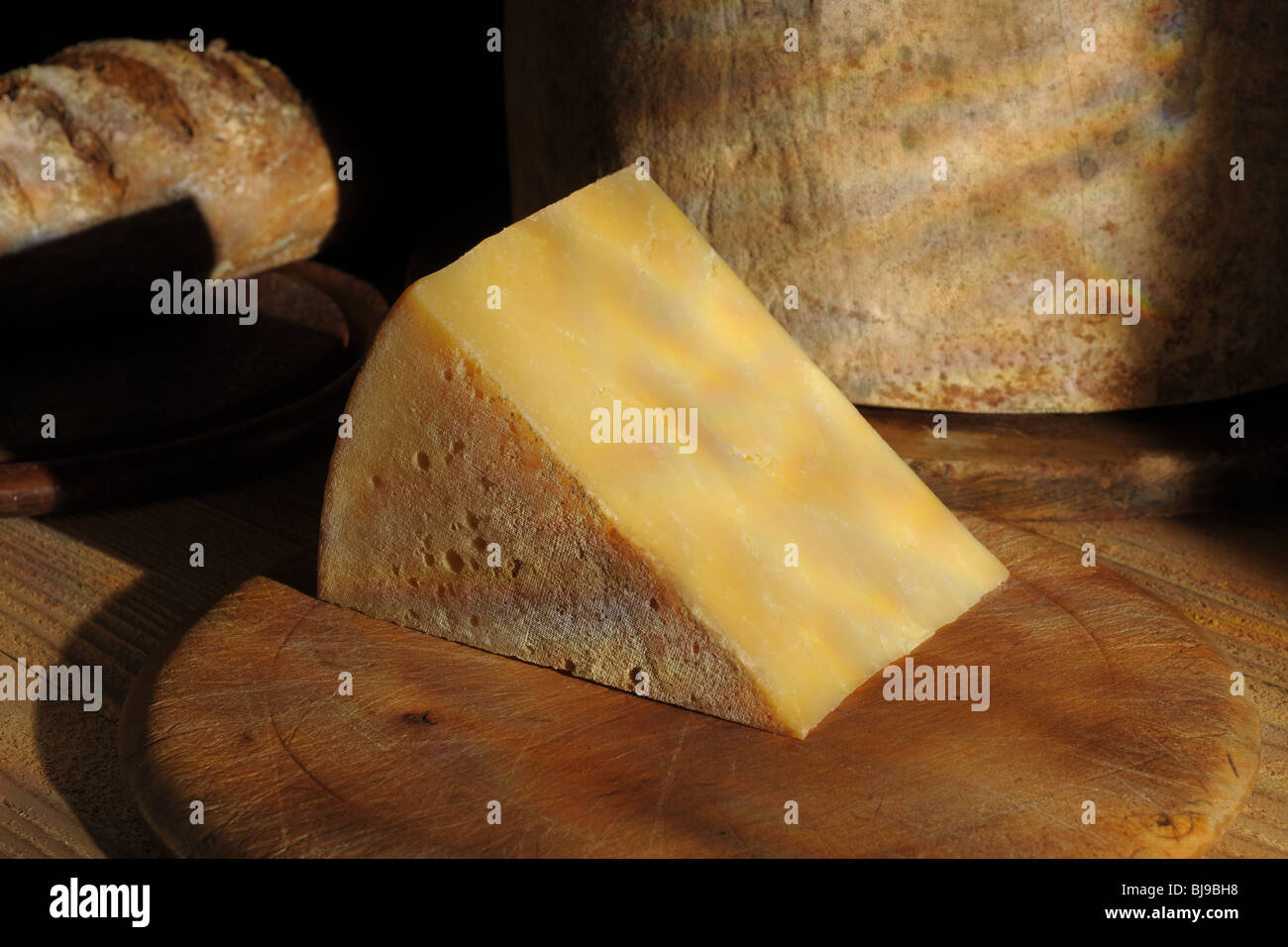 Cuneo di maturare il formaggio cheddar con a bordo tutto il formaggio e  pane in background Foto stock - Alamy