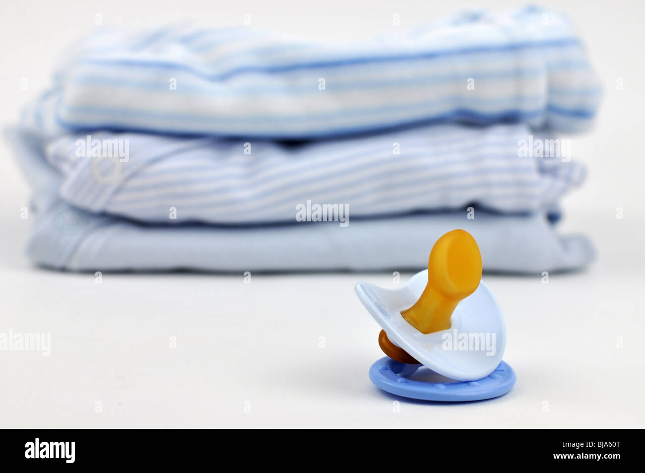 Il succhietto e un mucchio di blu vestiti del bambino Foto Stock