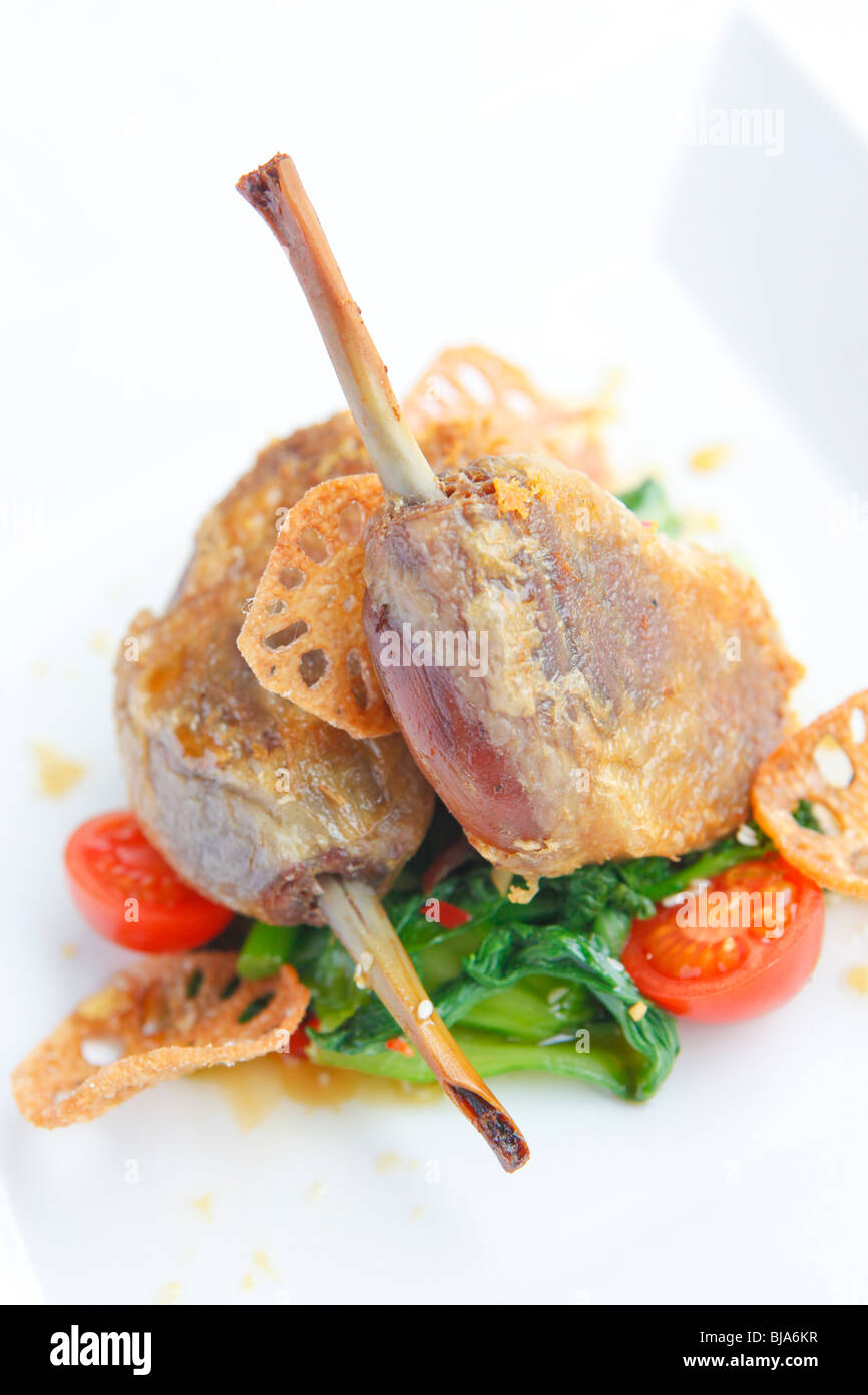 Duck gambe su un letto di pak choi con pomodori ciliegia. Foto Stock