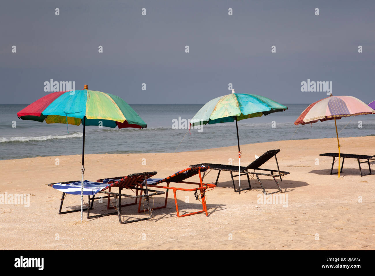 India Kerala, Varkala Beach, colorati ombrelloni e sdraio vuota Foto Stock